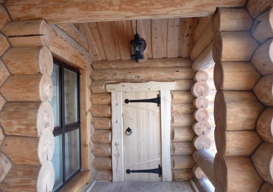 В деревянном доме отлично смотрится дверь из аналогичного материала с металлическими элементами 